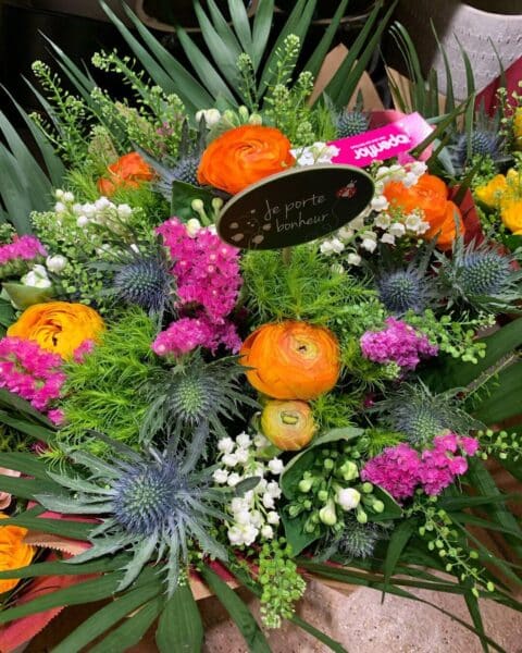 Bouquet de Muguet et Renoncules Coloré – Openflor Lille Bouquet de muguet du 1er mai avec renoncules orange, chardons bleus et pic porte-bonheur chez Openflor Lille.