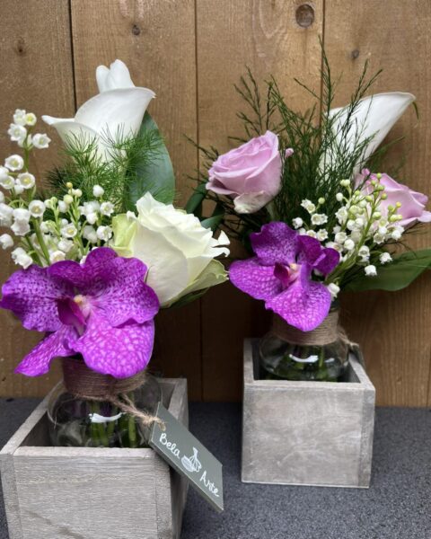 Composition Muguet et Orchidée Vanda – Fleuriste Lille Duo de compositions florales en pots bois avec muguet, orchidée Vanda violette et roses blanches, Openflor Lille.