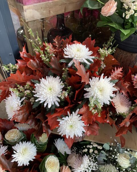 Composition Chrysanthèmes Blancs et Feuilles de Chêne – Toussaint Lille Composition florale pour la Toussaint avec chrysanthèmes blancs et feuilles de chêne rouges, fleuriste Lille.