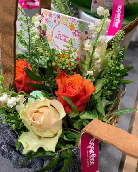 Sac Cadeau Muguet et Roses de Printemps – Openflor Petit sac en tissu garni de muguet, roses orange et message "Je sème du bonheur", Openflor Lille.