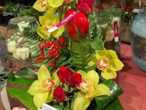 Composition exotique Love – Saint-Valentin Openflor Composition florale avec orchidées Cymbidium jaunes, roses rouges et pic décoratif "Love", Openflor Lille.