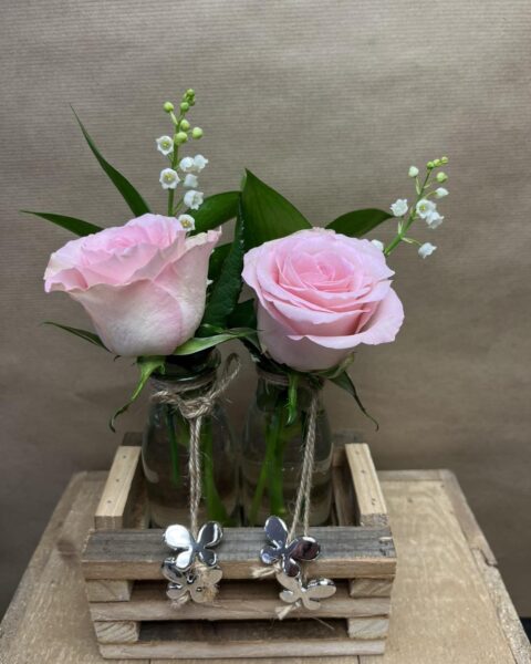 Duo romantique de roses et muguet – Openflor Duo de roses roses et brins de muguet dans de petits vases en verre et caisse en bois décorée de papillons, Openflor Lille.