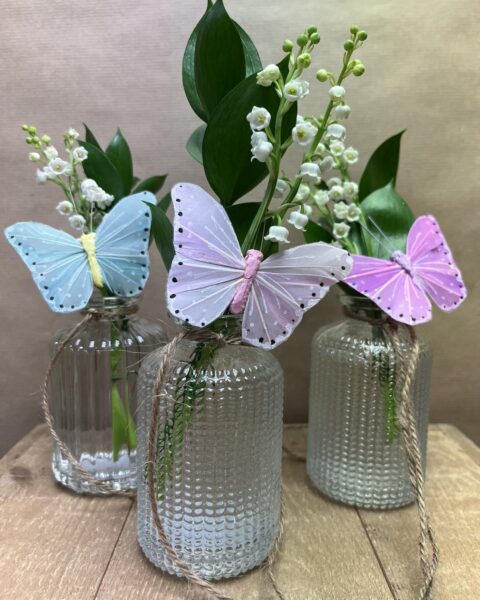 Composition muguet papillons de couleur – Openflor Trois vases en verre avec brins de muguet ornés de grands papillons décoratifs bleu, rose et violet, Openflor Lille.