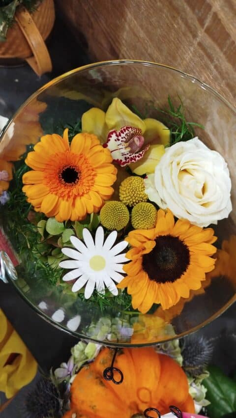 Coupe Florale Tournesol Orchidée et Gerbera – Décoration Lille – Openflor Composition florale vue du dessus dans une coupe en verre avec tournesol, orchidée jaune et roses, Openflor Lille.