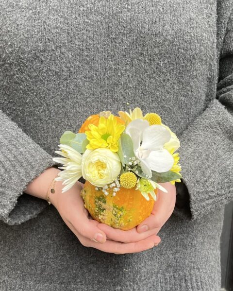 Mini Courge Fleurie avec Roses et Orchidée Blanche – Cadeau Automne Lille Petite courge orange décorée de fleurs blanches (rose, orchidée) tenue à la main, création artisanale Openflor Lille.