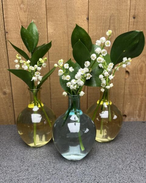 Trio de Vases Ronds et Brins de Muguet – 1er Mai – Lille – Openflor Trois petits vases ronds en verre garni de brins de muguet frais et de feuillage vert, décoration de printemps chez Openflor Lille.