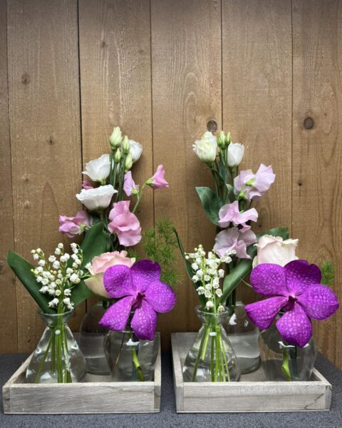 Compositions Muguet Pois de Senteur et Orchidée Vanda – 1er Mai – Lille – Openflor Plateaux en bois décoratifs avec muguet, orchidées Vanda violettes et pois de senteur dans de petits vases, fleuriste Openflor Lille.