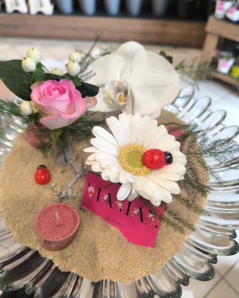 Coupe zen sur lit de sable – Rose et Gerbera blanc Composition zen dans une coupe en verre avec sable, rose, gerbera blanc et coccinelle, Openflor Lille.
