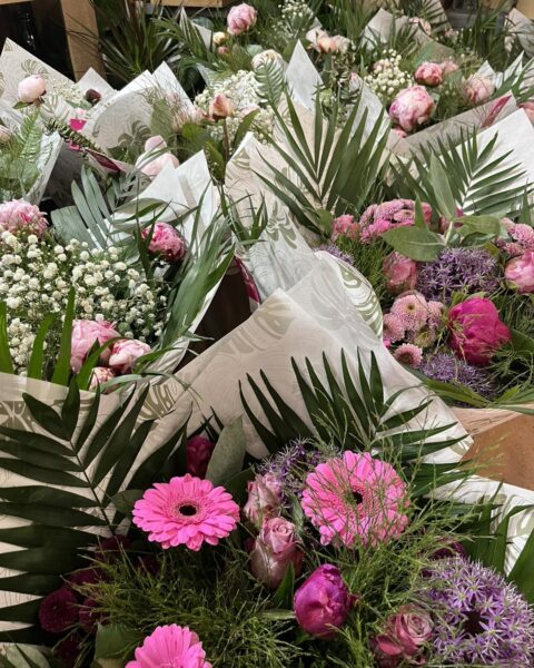 Étalage de bouquets Fête des Mères – Pivoines, gerberas et alliums Étalage de bouquets pour la fête des mères avec pivoines, gerberas roses et alliums violets, boutique Openflor Lille.