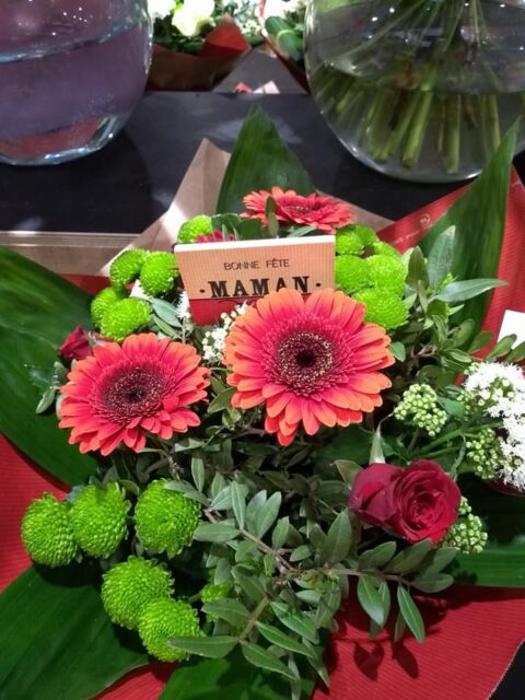 Bouquet de gerberas et roses rouges – Bonne Fête Maman Bouquet rond composé de gerberas et roses rouges avec lettrage Bonne fête maman, artisan Openflor.