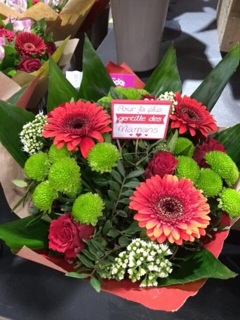Bouquet gerberas rouges et santini vert – La plus gentille des mamans Bouquet contrasté de gerberas rouges et santini vert avec pancarte Pour la plus gentille des mamans, Openflor.