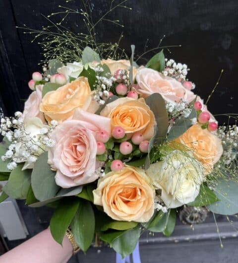 Bouquet de mariée pastel – Roses et Eucalyptus Bouquet de mariée aux teintes pastel avec roses pêche, hypericum et feuillage d'eucalyptus, Openflor Lille.