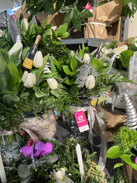 Compositions festives en vase – Tulipes blanches et Champagne Compositions florales en vase avec tulipes blanches, feuillage hivernal et champagne pour le Nouvel An, Openflor Lille.