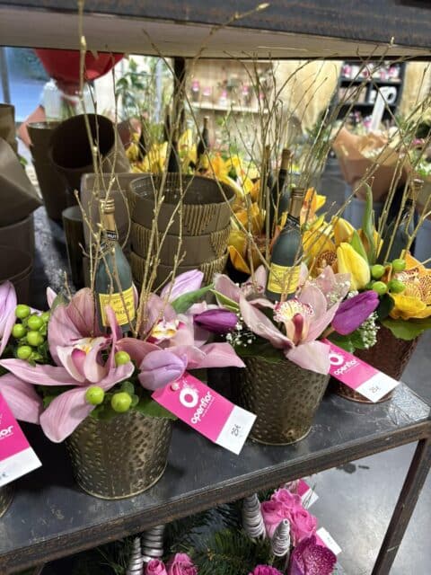 Coupe dorée du Nouvel An – Orchidées et Tulipes Coupe dorée festive avec orchidées roses, tulipes, millepertuis et petite bouteille de champagne, Openflor Lille.