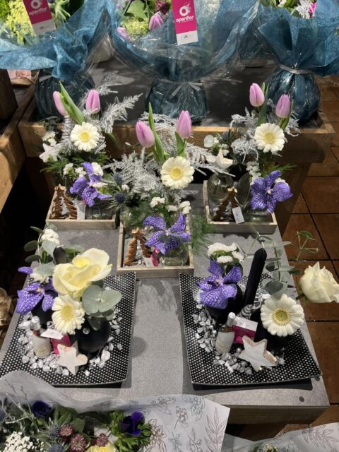 Décoration de table du Nouvel An – Orchidée Vanda et roses Décoration de table festive pour le Nouvel An avec orchidée Vanda, roses blanches, bougie et accessoires scintillants, Openflor Lille.