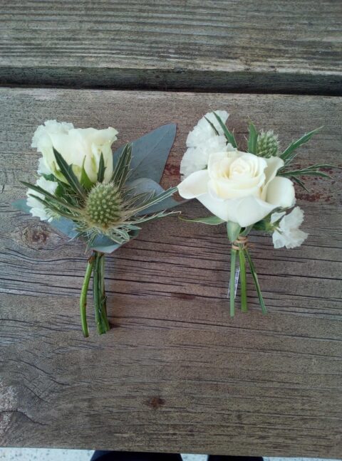 Duo de boutonnières de mariage – Rose blanche et chardon bleu Duo de boutonnières de mariage avec rose blanche, chardon bleu et eucalyptus, création Openflor.