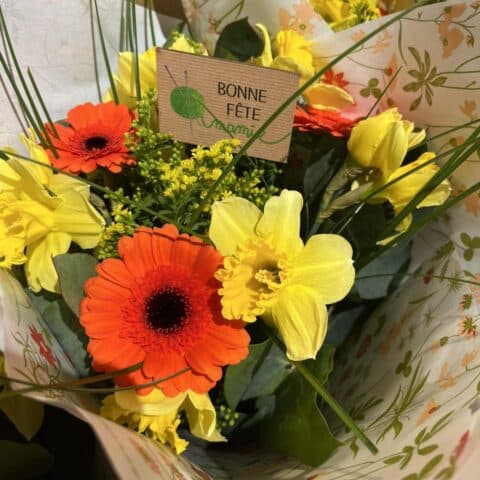 Bouquet gerberas oranges et jonquilles jaunes – Étiquette pelote de laine Bouquet radieux de gerberas oranges et jonquilles jaunes avec une étiquette pelote de laine, boutique Openflor.