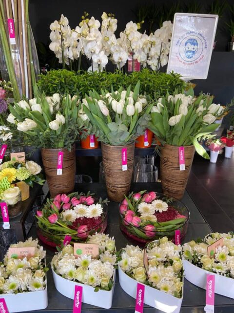 Étalage Fête des grands-mères : Tulipes blanches et compositions en cœur Étalage intérieur de fleuriste Openflor avec grands vases de tulipes blanches et compositions florales en forme de cœur.