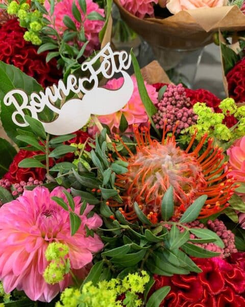 Bouquet exotique – Protea, dahlias et pic moustache Bouquet exotique et original avec protea, dahlias roses et pic décoratif moustache, Openflor.
