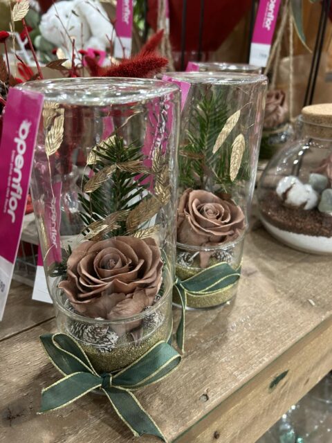 Roses éternelles chocolat en cylindre de verre Roses éternelles couleur chocolat dans des cylindres en verre avec feuillage doré et sapin, création de Noël Openflor.