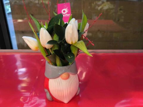 Tulipes blanches dans un pot lutin de Noël Tulipes blanches fraîches présentées dans un pot en céramique en forme de lutin de Noël, artisan fleuriste Openflor Lille.
